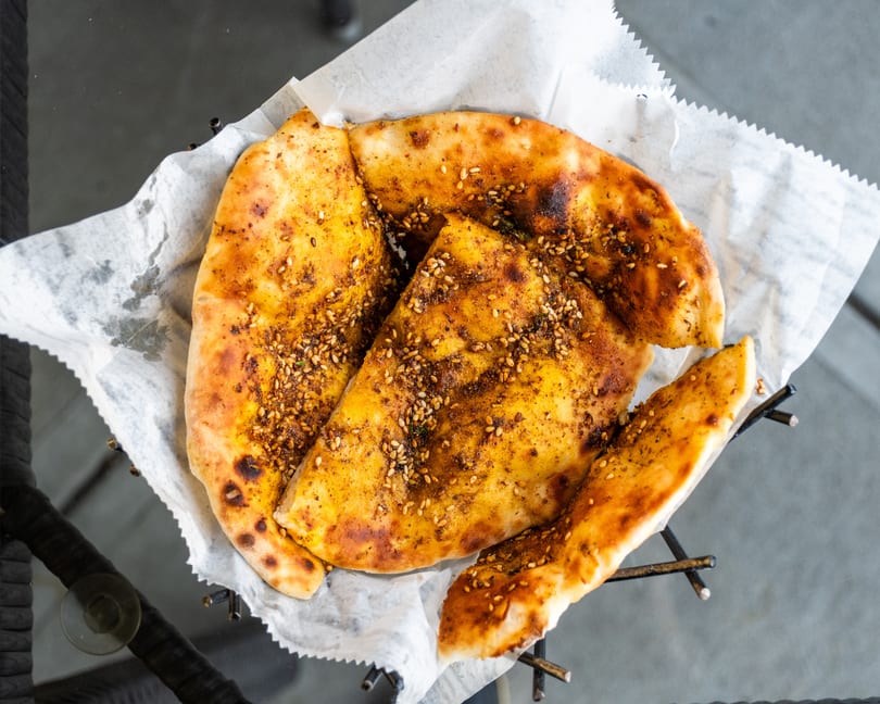 Za'atar bread, a Middle Eastern flatbread topped with herbs and sesame seeds, served in a basket.